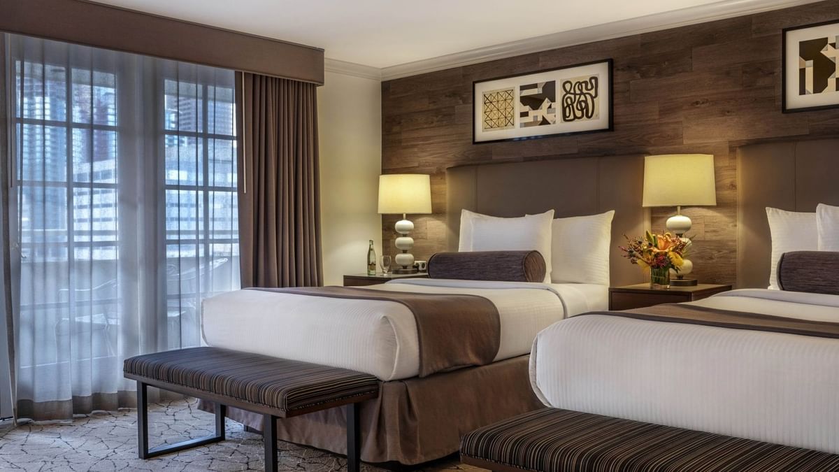 Twin beds by striped benches under a wood-paneled wall in Deluxe Rooms at Warwick Denver