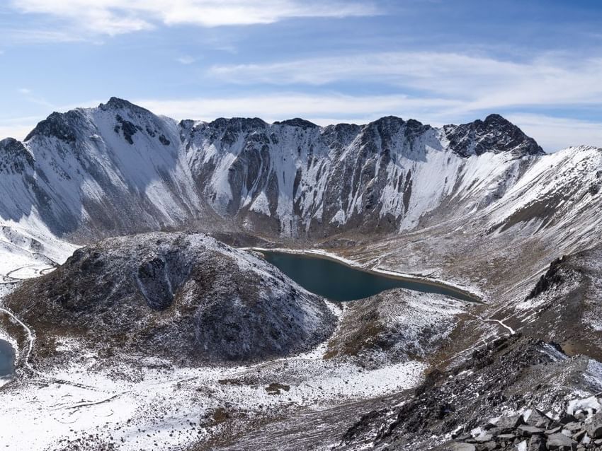 Lago de cráter de gran altitud rodeado de montañas nevadas cerca de Camino Real