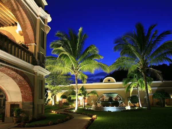A view of a night at the hotel with palm trees