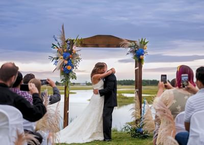 Wedded couple hugging in an outdoor wedding venue by the estuaries at Ogunquit River Inn