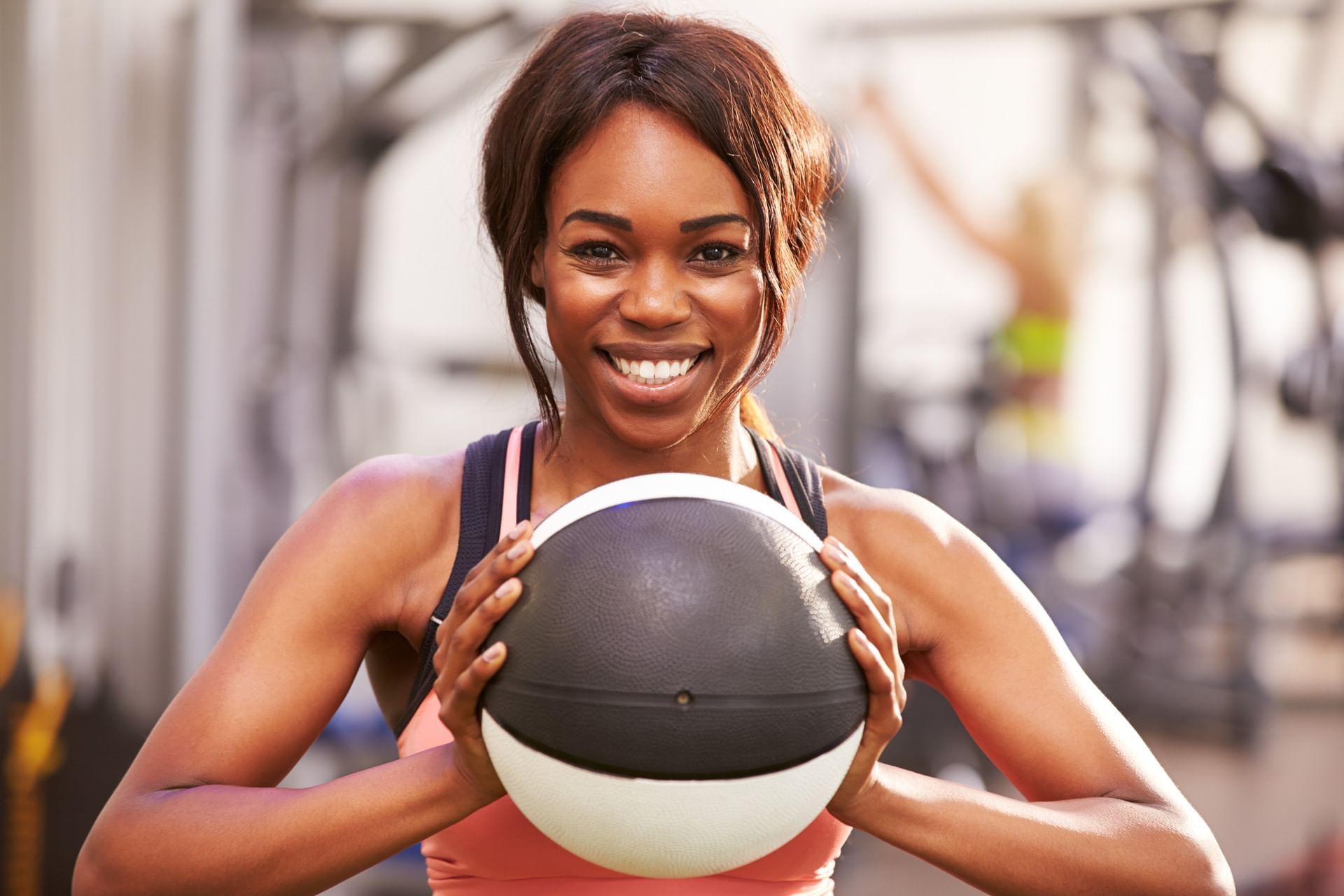 A woman in a gym holding a medicine ball.