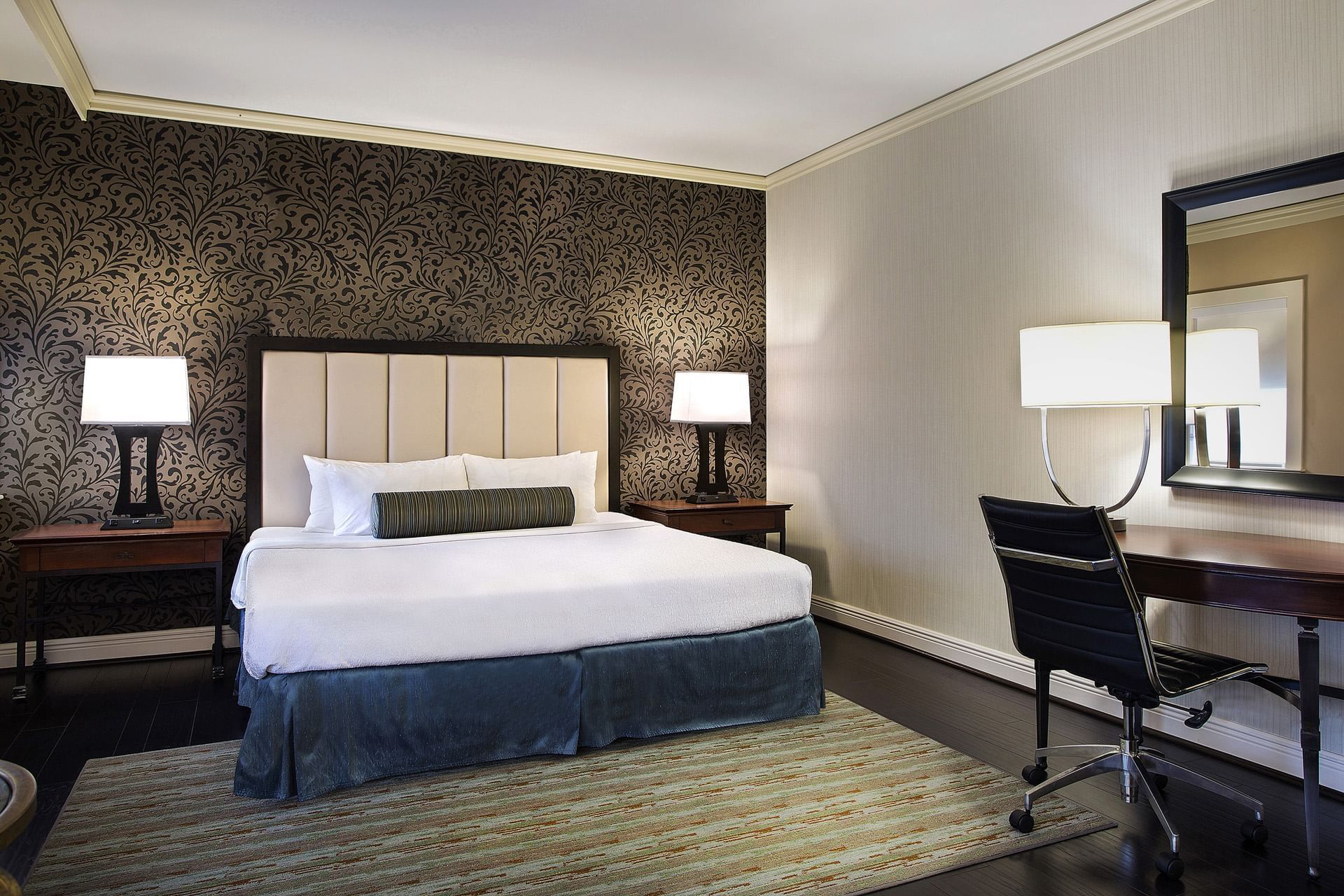 A hotel room with a bed, desk, and chair