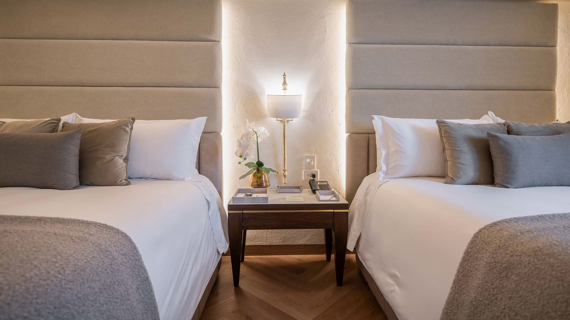 Two queen beds with pillows and blankets next to a nightstand at Quinta Real Puebla in Heroica Puebla de Zaragoza.