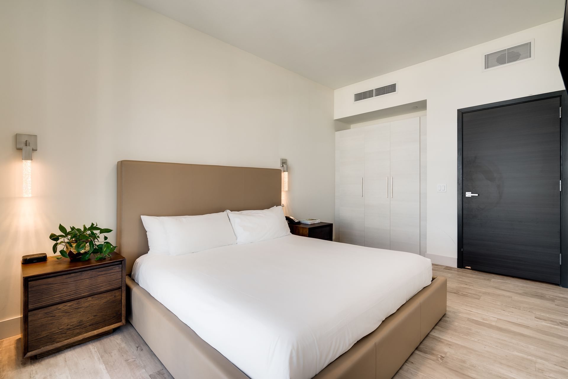 A clean and modern hotel room with a large bed, wooden nightstands, and a closet.