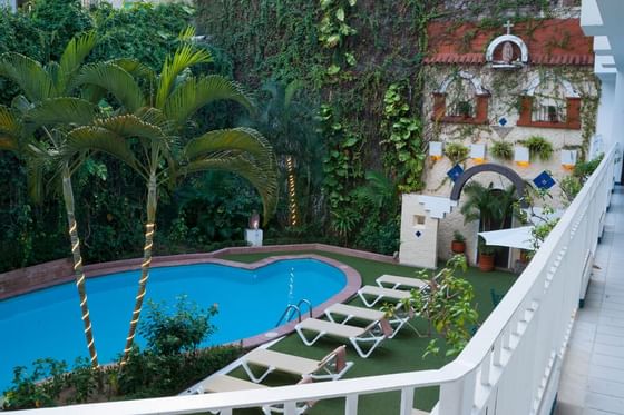 piscina exterior con jardín y tumbonas