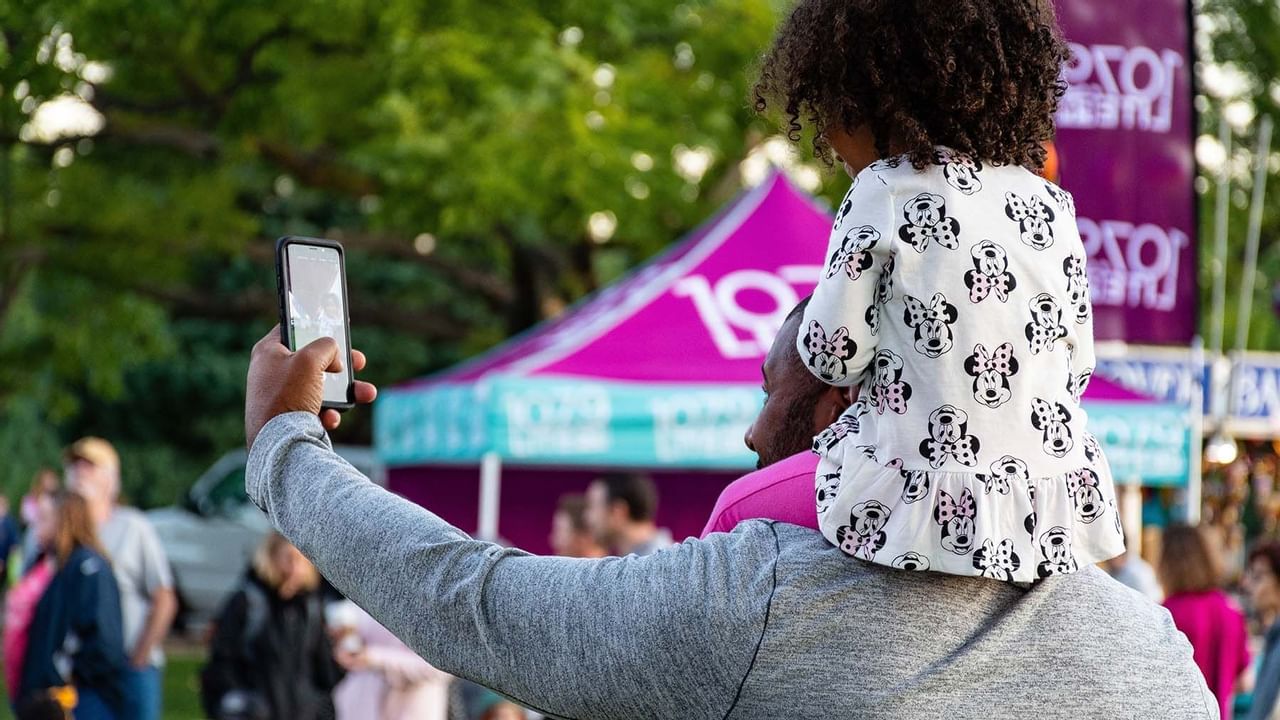 Father taking a selfie with daughter on his shoulders