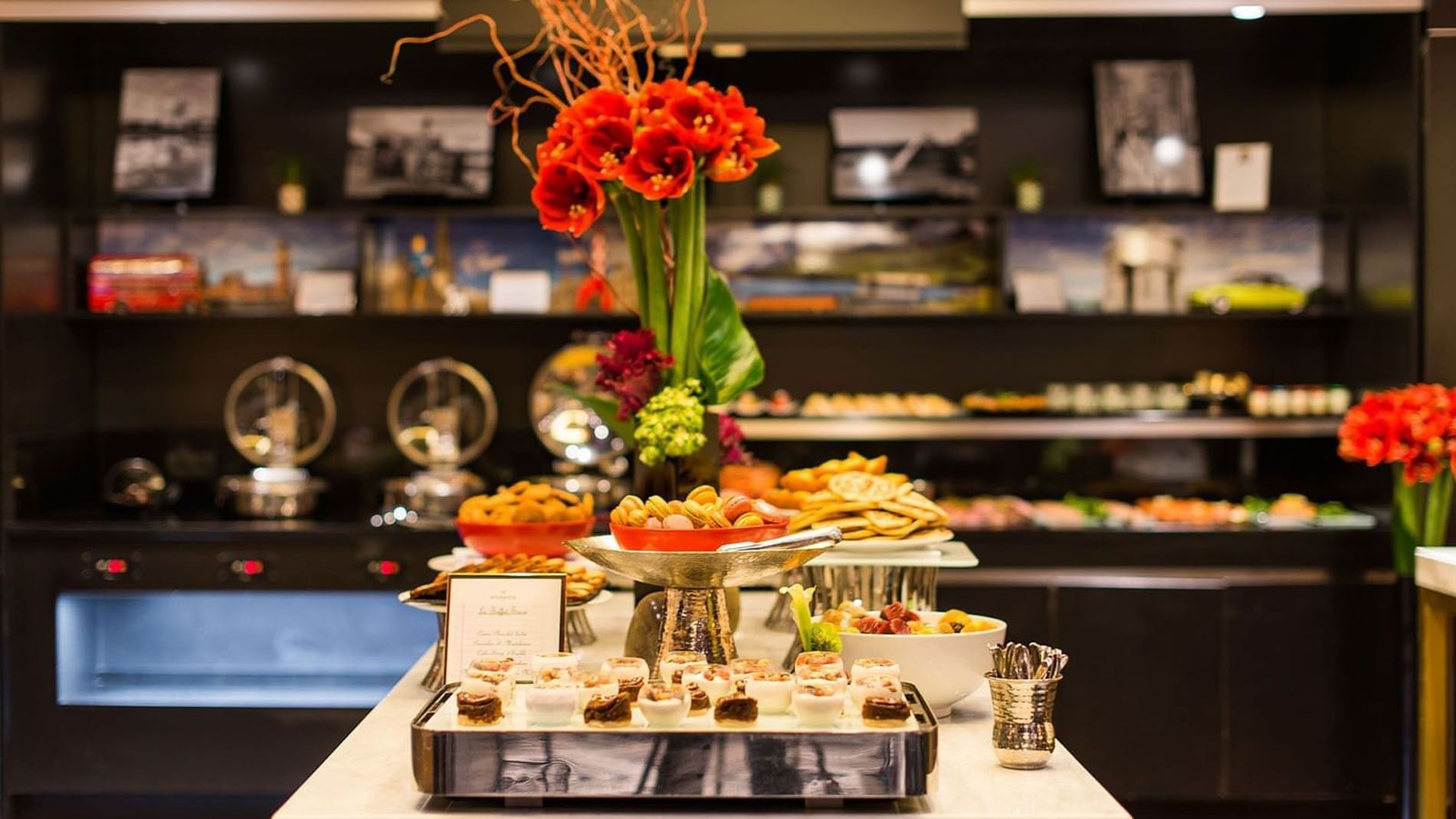 A buffet table with various food items and flowers