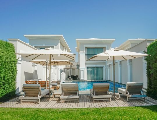 Sun loungers with patio umbrellas by pool deck at Exclusive Pool Villa in Titanic Deluxe Golf Belek