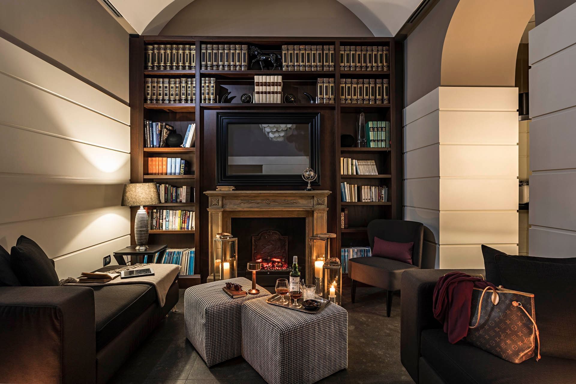 Softly lit lobby at The Independent with bookshelves, fireplace, comfy seating, and a table with drinks and snacks