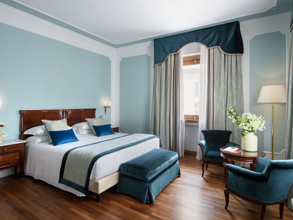 Large bed & blue chairs with coffee table in Deco Superior Room at Bettoja Hotel Mediterraneo