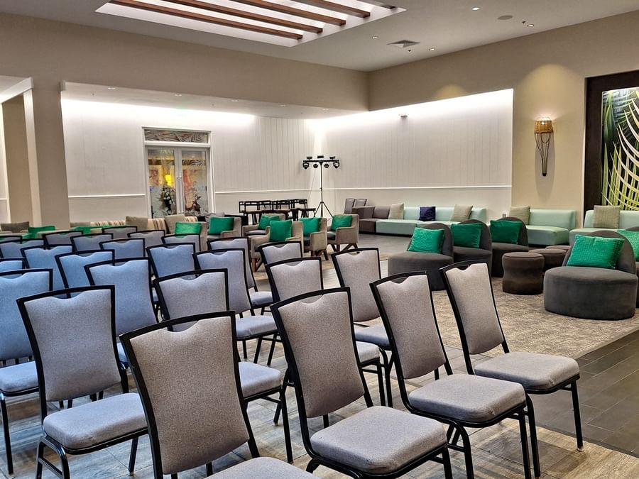 Grey chairs by plush sofas under a high ceiling surrounding a wide carpet at Warwick Paradise Island Bahamas
