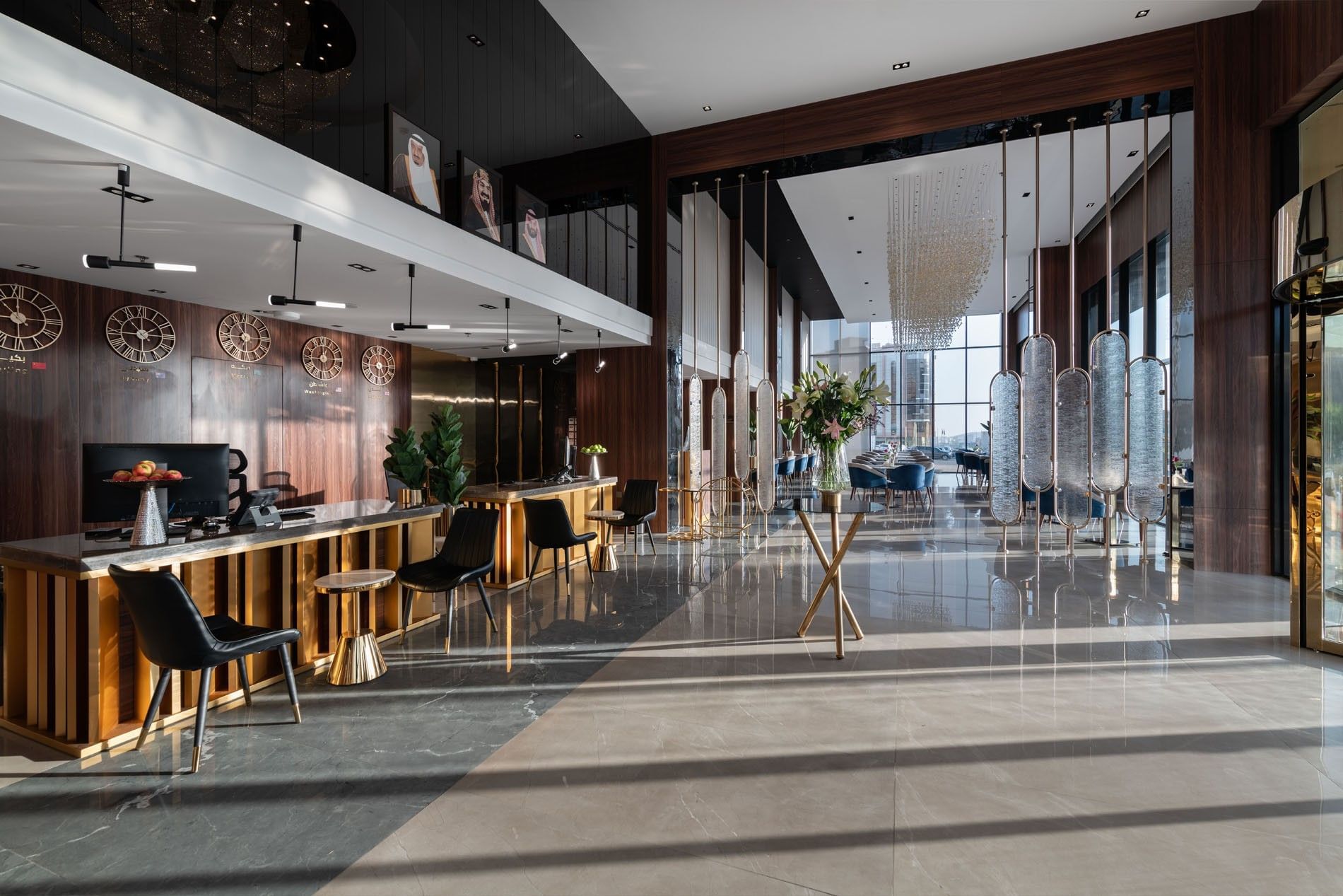 Lobby desks by black chairs under wall clocks and a mezzanine level at Warwick Al Taif Hotel