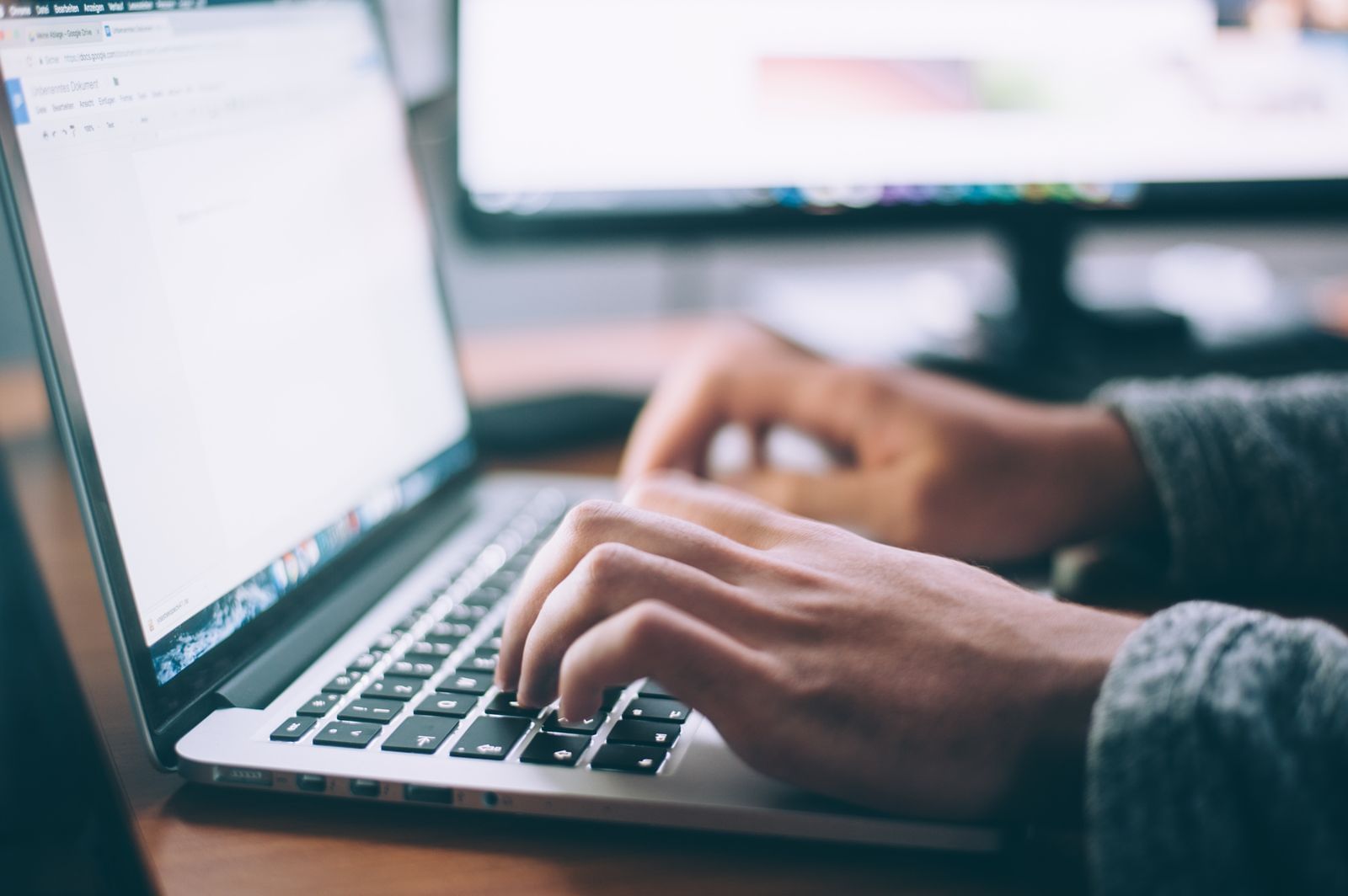 Hands typing at a laptop