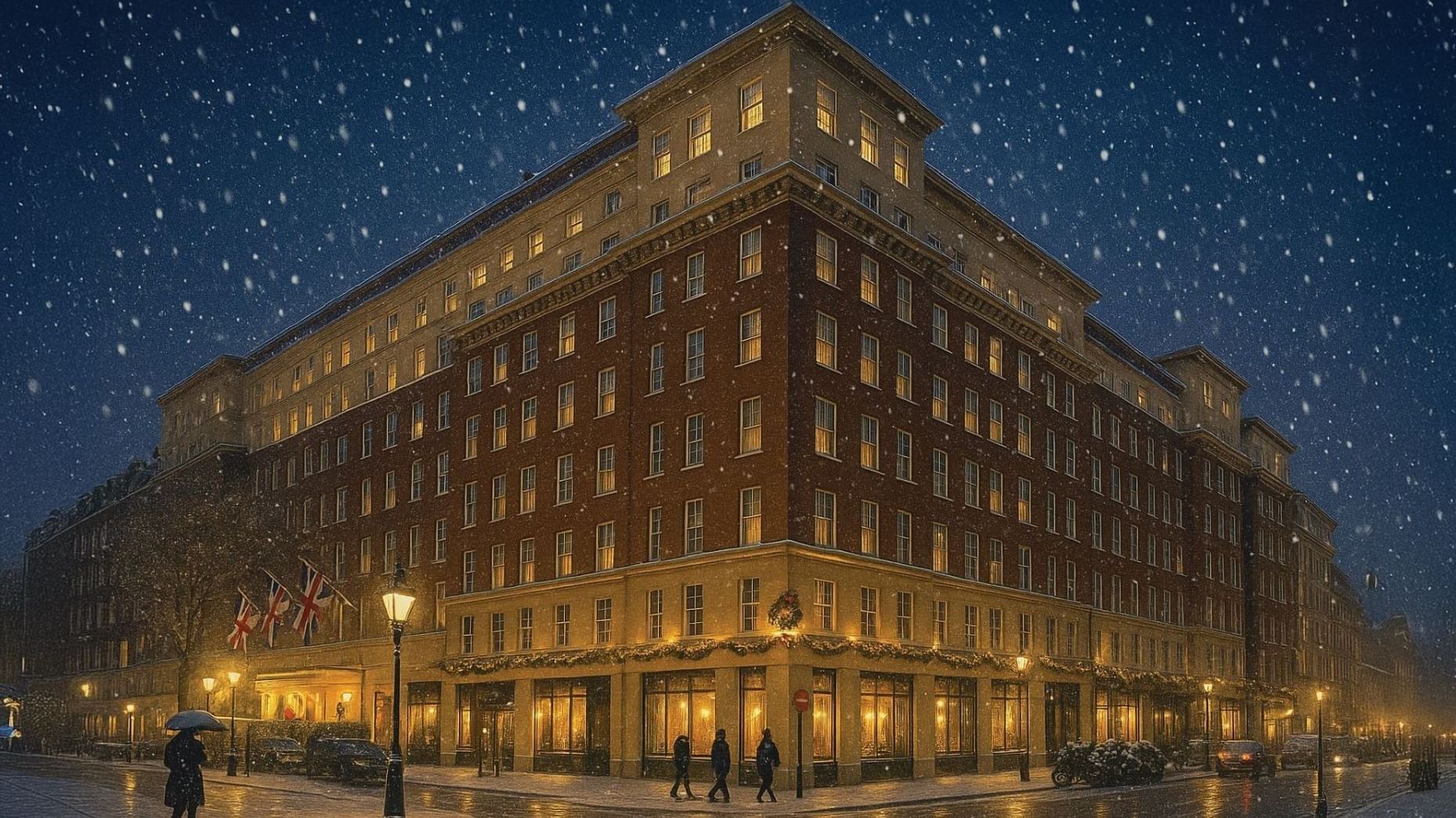 Hotel building illuminated at night with falling snow and pedestrians on the street at The May Fair Hotel, London