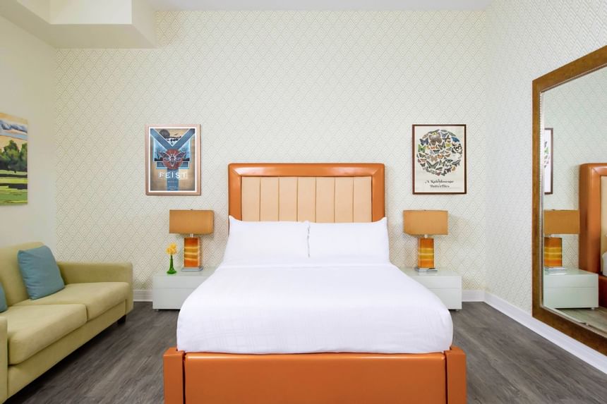 queen bed with orange leather bedframe and a large mirror and co
