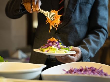Chef adding salad ingredients to a plate at Al Firdous Restaurant, Saja by Warwick Madinah.