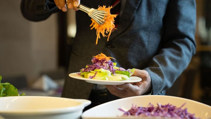Man adding vegetables to salad at Saja by Warwick Madinah.