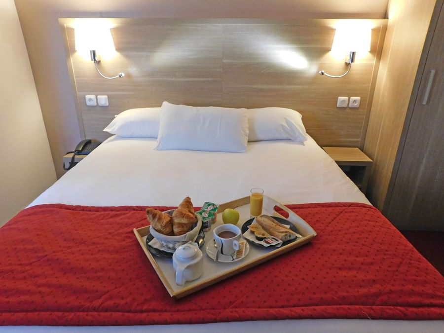 Breakfast served on a king bed in a room at Hotel Ambacia