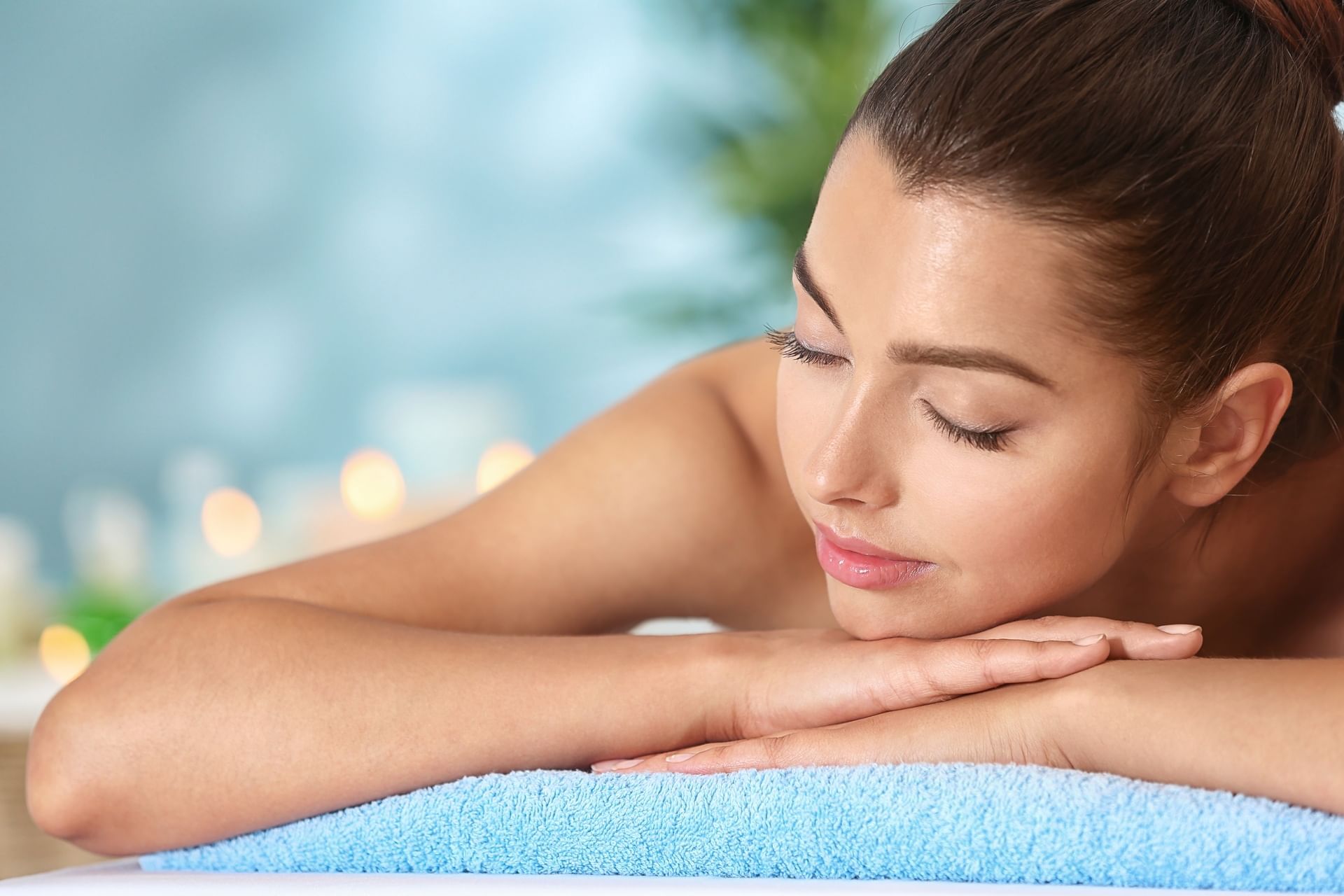 Woman resting comfortably with eyes closed on a soft blue towel during a spa massage at El Conquistador Resort