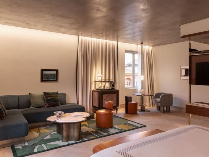 Spacious 1 King Bed Junior Suite with modern seating area, decorative ceiling, and city views at The Thompson Rome, Roma.