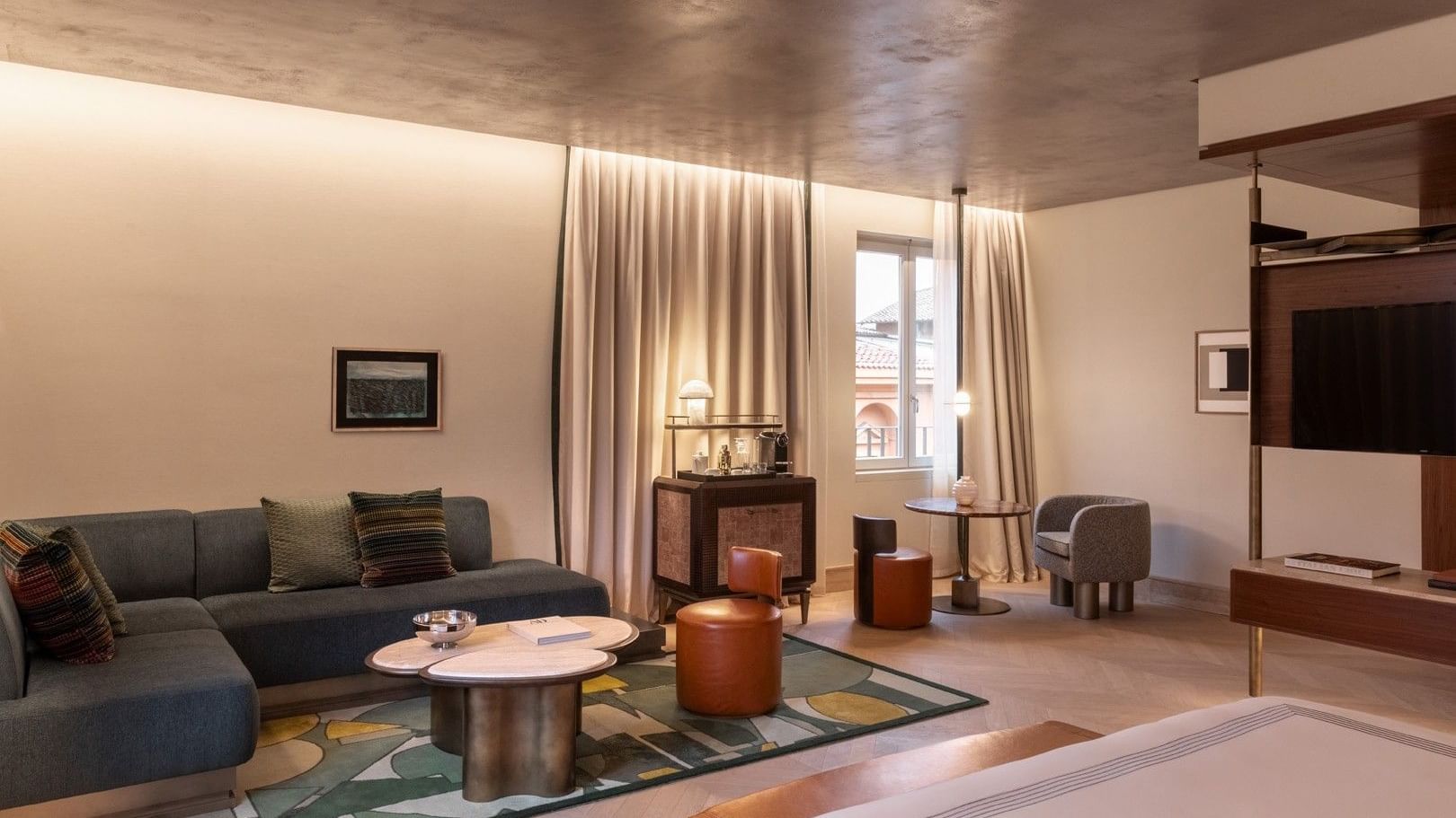 Spacious 1 King Bed Junior Suite with modern seating area, decorative ceiling, and city views at The Thompson Rome, Roma.