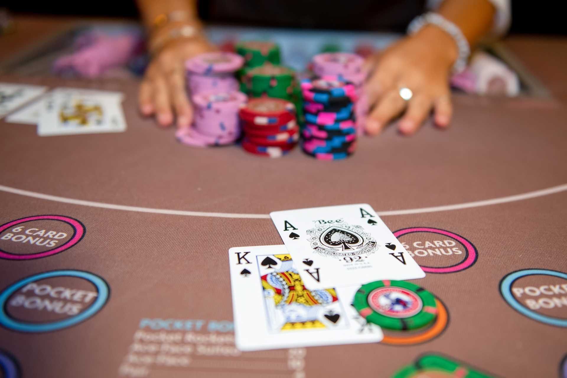Casino blackjack table with an ace, king and betting chips placed before colorful chip stacks at The Brook