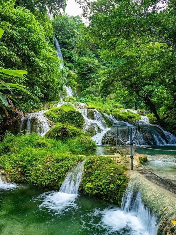 Mele Cascade Waterfalls cascading through a vibrant and green tropical jungle near the Warwick Le Lagon
