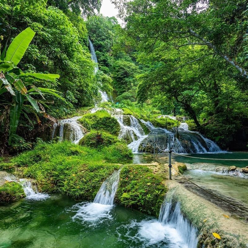 Mele Cascade Waterfalls cascading through a vibrant and green tropical jungle near the Warwick Le Lagon