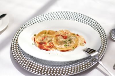 Two ravioli filled with green filling, topped with red chili slices & herbs served in Spices Restaurant at Bay Gardens Hotel