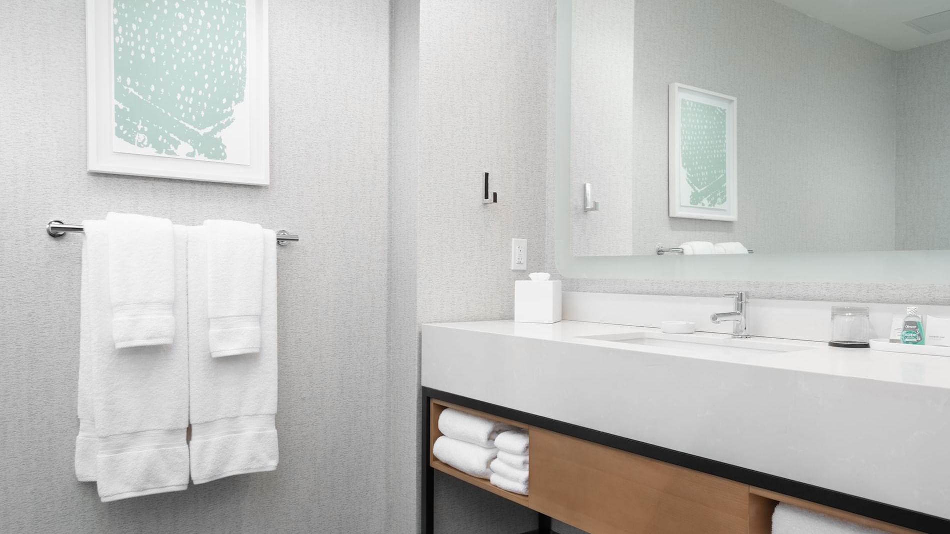 A modern bathroom with a large mirror, white towels, and a clean sink area.
