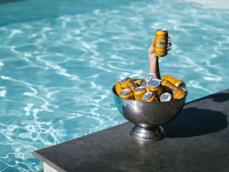 Hand holding beer can in bowl by pool at Pullman Sydney Hyde Park