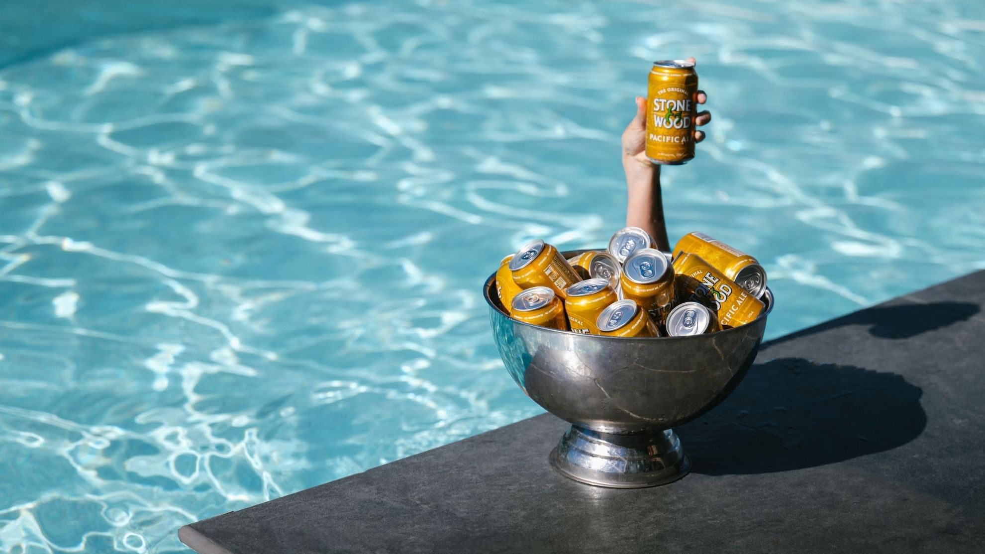 Hand holding beer can in bowl by pool at Pullman Sydney Hyde Park