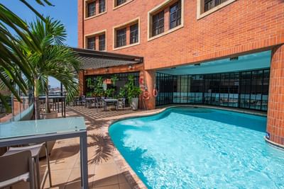 Indoor pool with turquoise water, surrounded by tiled flooring and lush greenery in Wet zone at Dann Carlton Cali