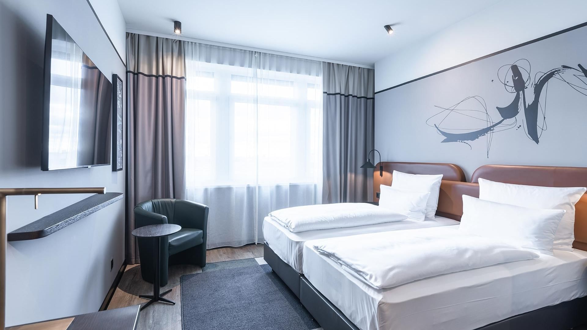 Twin beds with wall art and TV in Classic Room at Titanic Comfort Kurfürstendamm