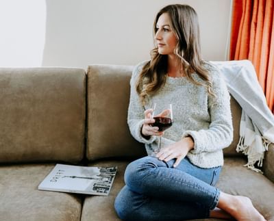 Young lady on a couch with a glass of red wine at Adara Hotel