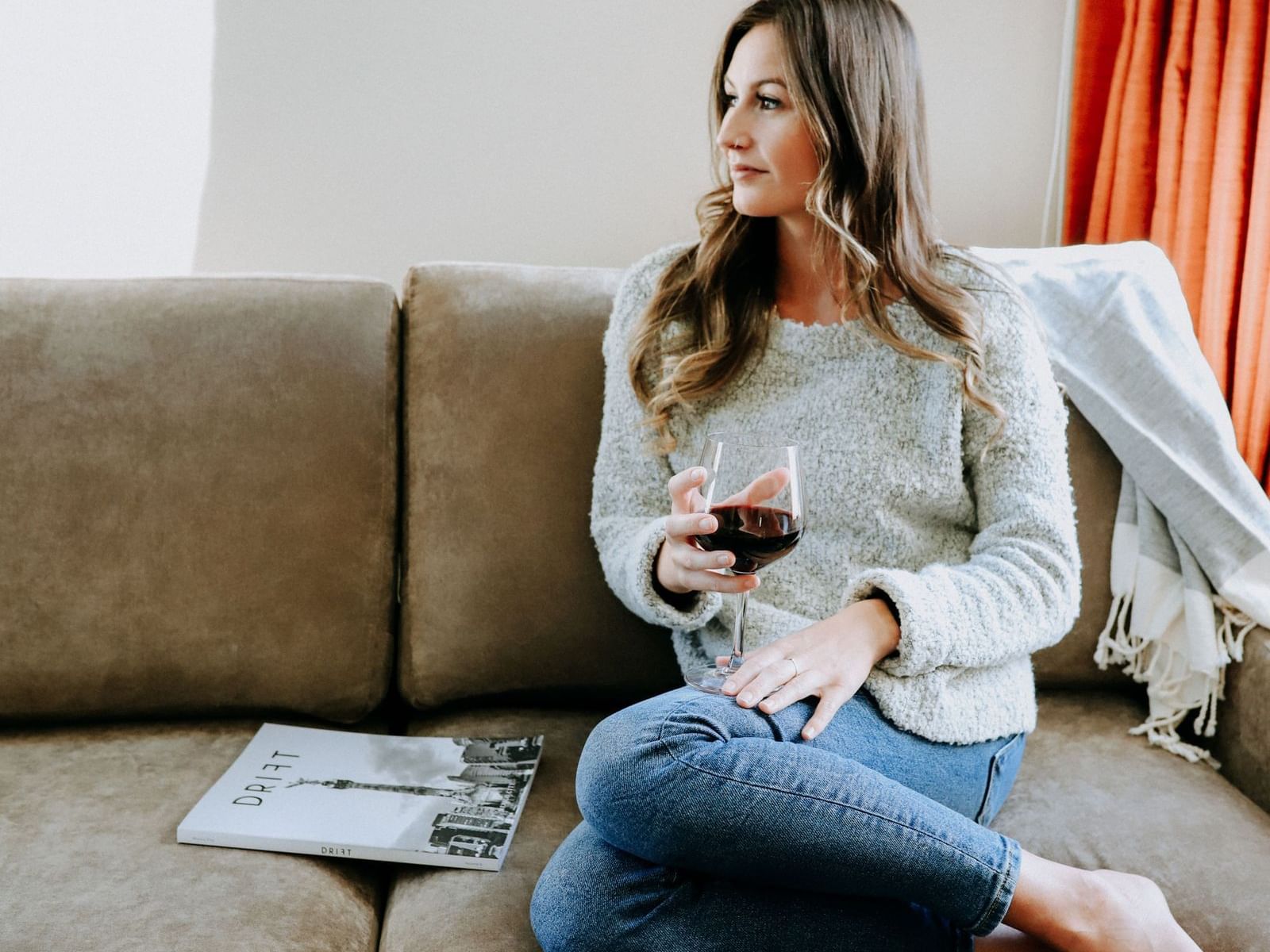 Young lady on a couch with glass of red wine.