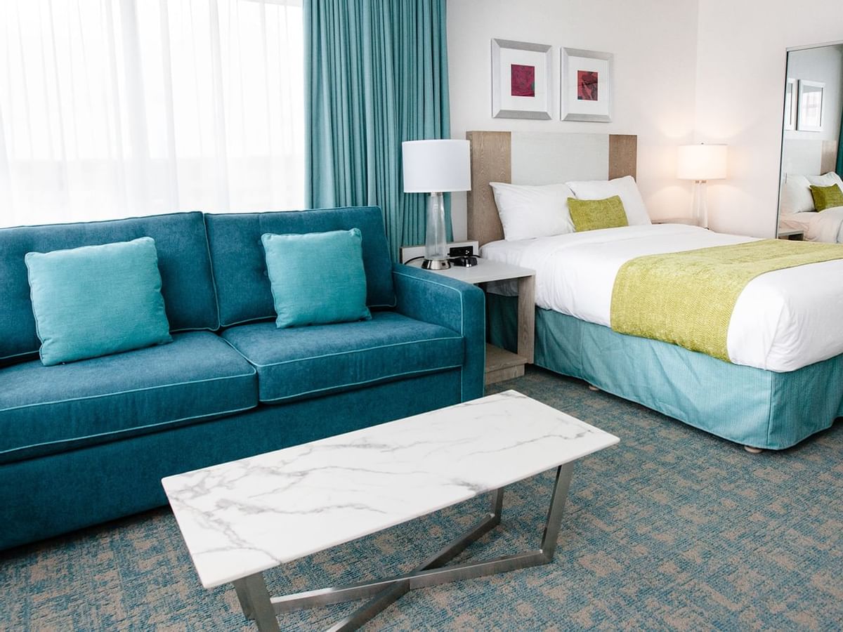 Blue sofa bed with coffee table beside a queen bed