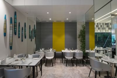 Indoor dining area with arranged tables in The Glass House at Eastin Residences Vadodara