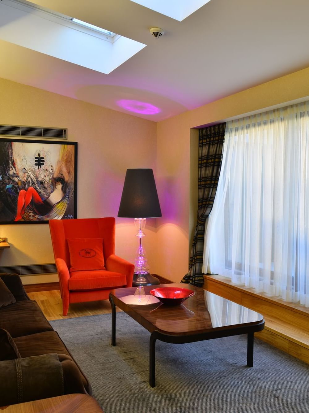 Brown sofa by a red armchair surrounding a coffee table in Ankara Suite with Terrace at Warwick Ankara