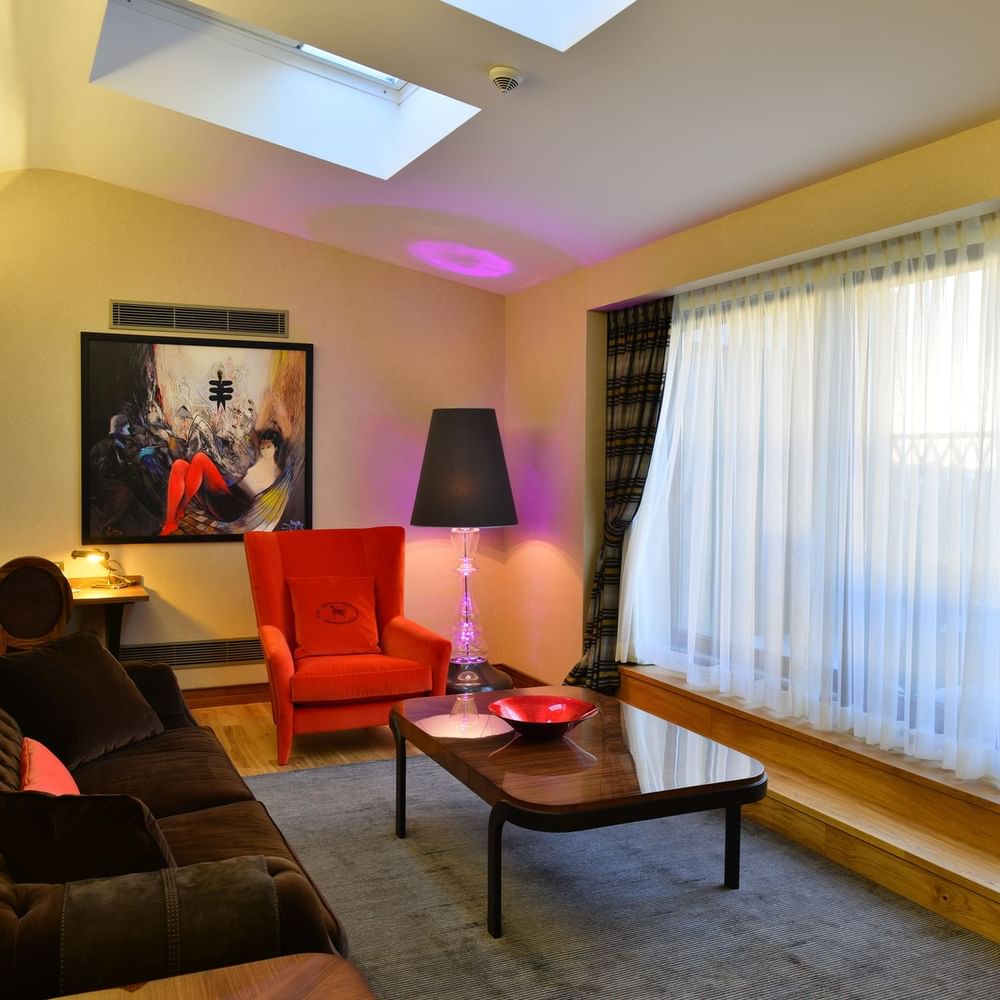 Brown sofa by a red armchair surrounding a coffee table in Ankara Suite with Terrace at Warwick Ankara