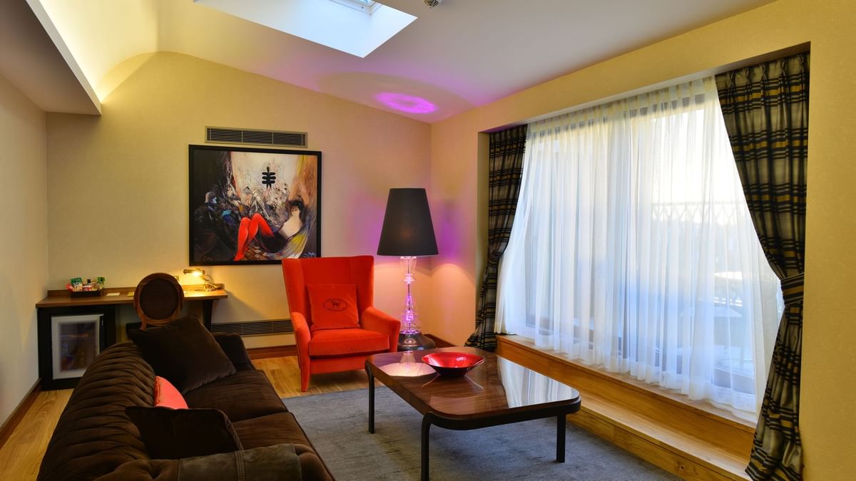 Brown sofa by a red armchair surrounding a coffee table in Ankara Suite with Terrace at Warwick Ankara