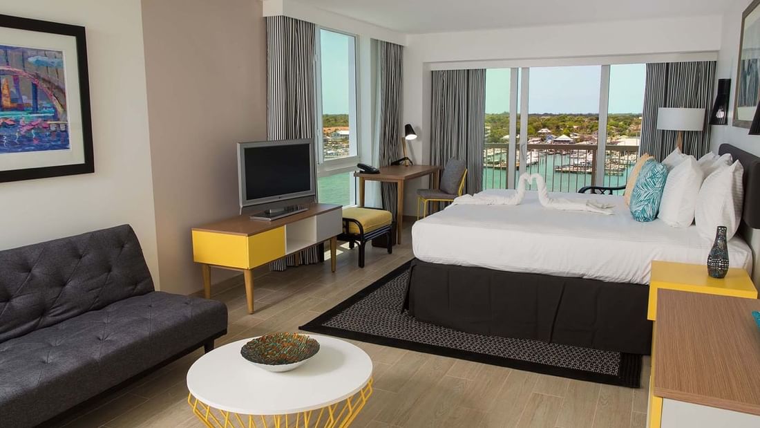 King-size bed, work desk, a TV & a cozy couch in Harbor Premium Balcony at Warwick Paradise Island Bahamas