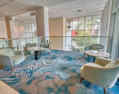Stylish lounge area with two plush chairs, a marble table, and a blue patterned carpet at Matrix Hotel