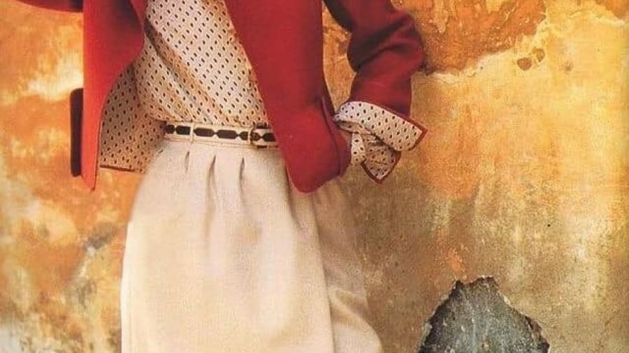 Woman in a red jacket and skirt posing by a wall near Rome Luxury Suites