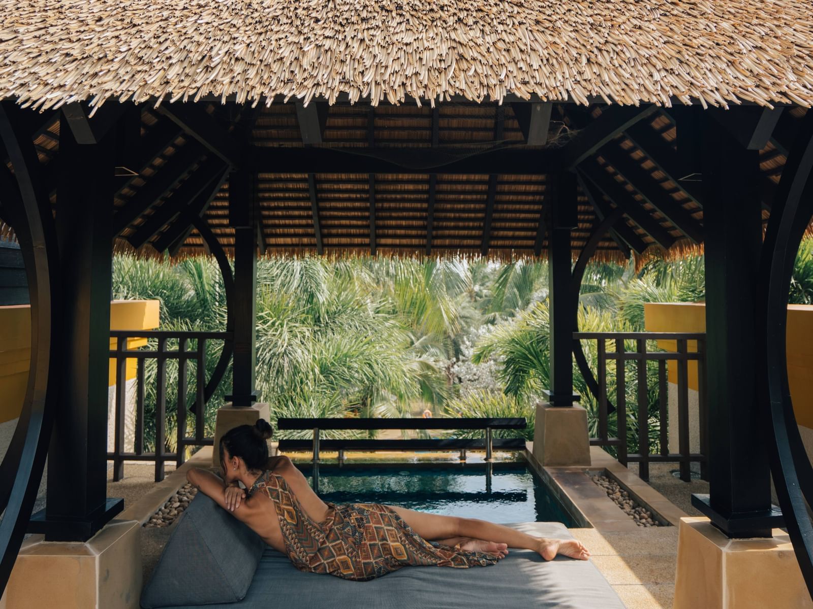 Woman lounging on a daybed near the plunge pool on the rooftop of The Penthouse Villa