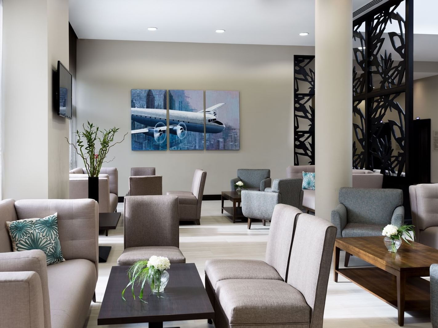 Lounge with soft seating, large airplane artwork on the wall, and green plants at Heston Hyde Hotel