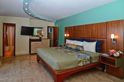King bed against a wood-paneled wall with curved ceiling lights in Hibiscus Honeymoon Suite at Lindbergh Bay Hotel & Villas