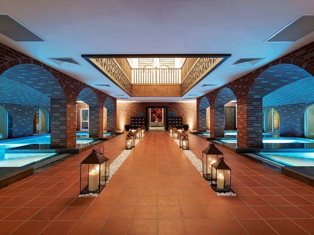 Indoor pool area with lanterns along a central walkway at Titanic Deluxe Golf Belek