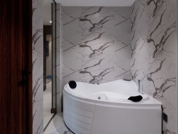 Modern bathtub in a bathroom with tiled walls at Warwick Hotel Al Taif