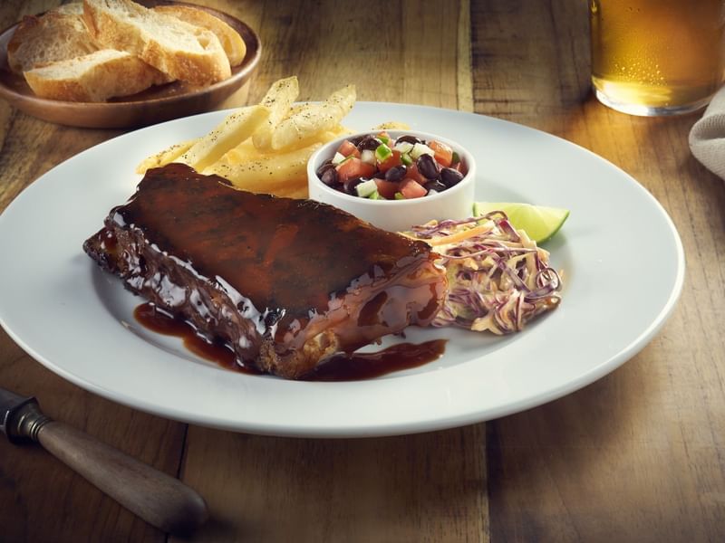 Plate of barbecue ribs with coleslaw, beans and chips served in Rosato at Fiesta Americana